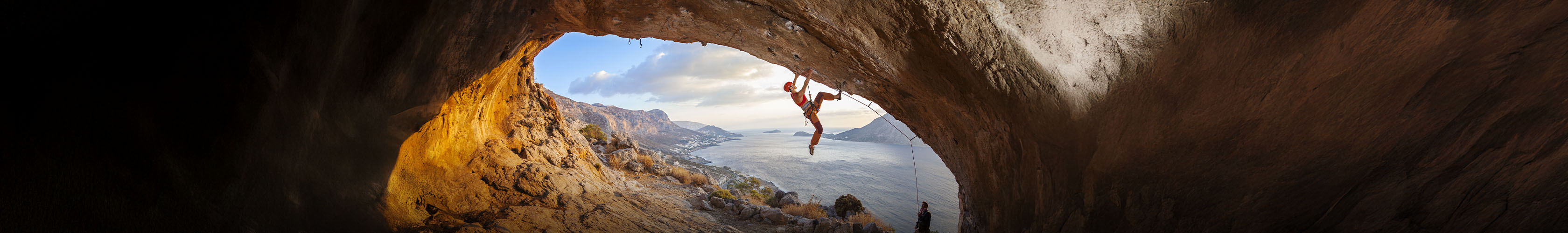 Shop climbing new season. A person climbing upside-down on a rock